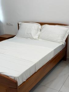 a bed with white sheets and pillows on it at Résidence L H in Yaoundé