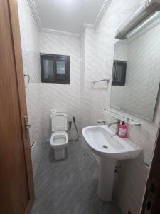 a bathroom with a sink and a toilet and a mirror at Résidence L H in Yaoundé +5 photos
