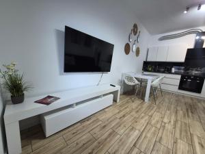 a white living room with a flat screen tv on a wall at Różana Piątka ul Oporowska 22 A in Kutno