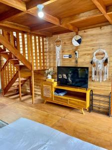 a living room with a tv and a wooden wall at Miarzafa Cabin House DIENG in Kejajar