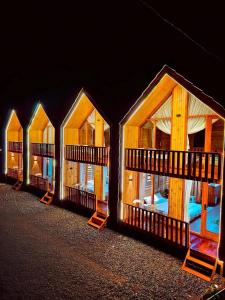 a row of wooden huts with windows at night at Miarzafa Cabin House DIENG in Kejajar