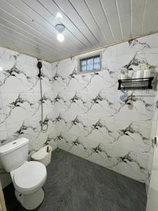 a bathroom with a toilet and a marble wall at Miarzafa Cabin House DIENG in Kejajar +15 photos