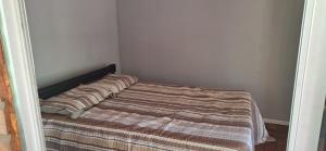 a small bedroom with a bed with a striped blanket at Casa ecologica artesanal in Santa Ana