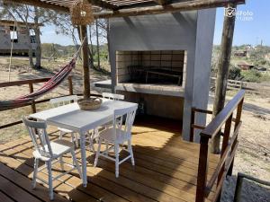 a table and chairs on a porch with a fireplace at OHANA in Punta Del Diablo