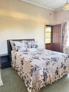 a bedroom with a bed with a black and white comforter at SashMc Flair Guesthouse in Klerksdorp