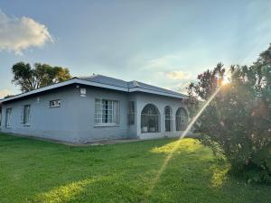 a white house with the sun setting behind it at SashMc Flair Guesthouse in Klerksdorp