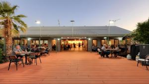 a building with people sitting at tables in front of it at Longreach Tourist Park in Longreach
