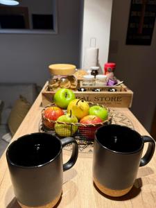 two cups on a table with a basket of apples at Espacio Nidra - Tu descanso a pasos del Aeropuerto in Ezeiza