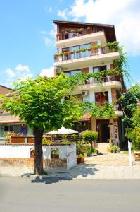 a building with a tree in front of it at Nirvana Guest House in Nesebar
