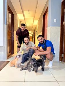 four men kneeling in a hallway with three dogs at Goofy Ants Hostel in Puerto Princesa City