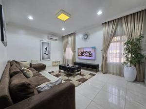 a living room with a couch and a table at Pavilion Luxury 4bedroom duplex in Mama