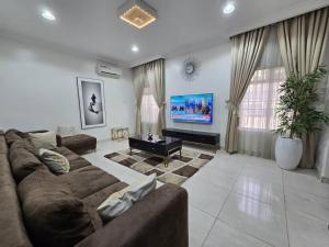 a living room with a large couch and a tv at Pavilion Luxury 4bedroom duplex in Mama +9 photos