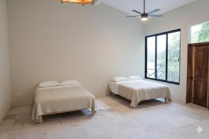 two beds in a room with white walls and a window at Casa Azul, Oceanfront Estate with Rooftop Deck in Yelapa