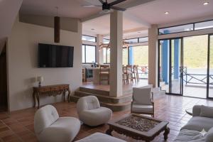 a living room with a couch and chairs and a tv at Casa Azul, Oceanfront Estate with Rooftop Deck in Yelapa