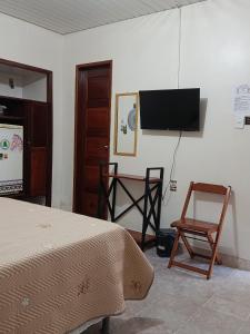 a bedroom with a bed and a tv and a chair at Pousada Pedra das Amazonas in Parintins