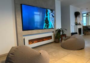 a living room with two chairs and a tv and a fireplace at Rheinpanorama Penthouse Neuss Düsseldorf in Neuss
