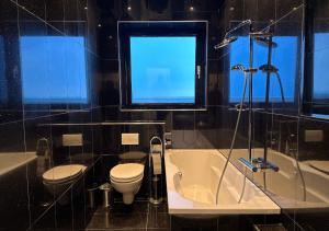 a bathroom with a toilet and a tub and a sink at Rheinpanorama Penthouse Neuss Düsseldorf in Neuss +5 photos