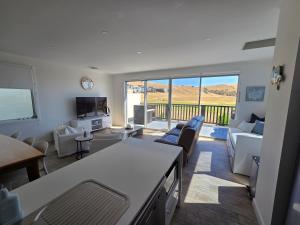 a living room with white furniture and a balcony at 3rd On Troon in Normanville