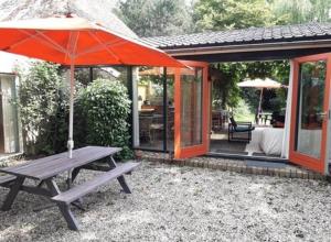 a picnic table with an umbrella in front of a house at Toplocatie voor je workshop! Of grote gezin! Zwembad! in Hurwenen