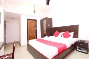 a bedroom with a large bed with red pillows at Hotel O Dwarika Inn in Jabalpur