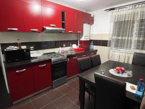 a kitchen with red cabinets and a table and a microwave at Apartament ALEX in Sibiu