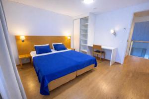a bedroom with a blue bed and a desk at Kylpyla Spa Villa Saimaan Harmonia in Imatra