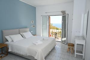 a white bedroom with a bed and a balcony at Panorama Apartments updated with infinity pool in Agios Nikolaos