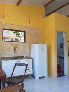 a kitchen with a refrigerator and a table and a chair at Villa Tropical Herbert in Itacaré