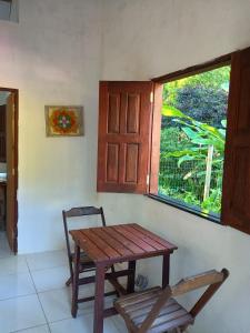 a wooden table and a chair in a room with a window at Villa Tropical Herbert in Itacaré