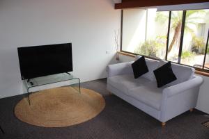 a living room with a couch and a flat screen tv at Nautilus Beach Apartment 109 in Coffs Harbour
