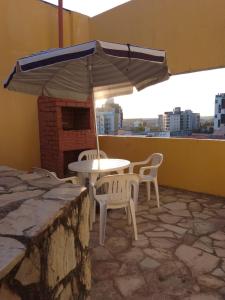 a table and chairs and an umbrella on a balcony at Apartamento com piscina e churrasqueira privativas in Cabedelo