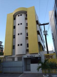a yellow and white building with a fence in front of it at Apartamento com piscina e churrasqueira privativas in Cabedelo