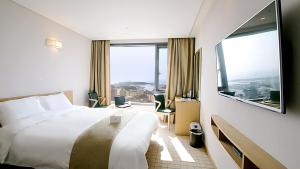 a hotel room with a bed and a large window at Mstay Hotel in Seogwipo