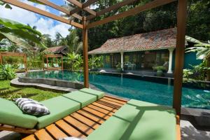 a swimming pool with a bench in front of a house at Darmada Eco Resort in Sidemen +63 photos