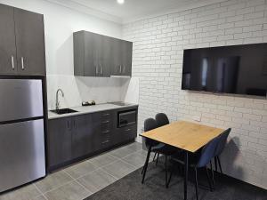 a kitchen with a table and a sink and a refrigerator at Blue Violet Motor Inn in Toowoomba