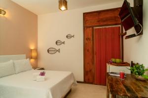 a bedroom with a bed and a tv and a door at Espaço Fateixa in Jericoacoara
