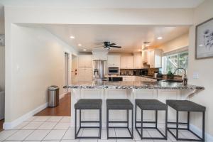 a kitchen with a bar with three stools at Your Poolside Hideaway in Bakersfield