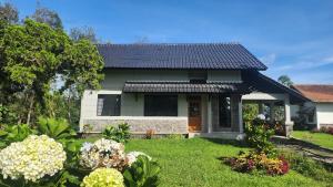 a small white house with a yard with flowers at Cypress Resort Cipanas in Barukupa