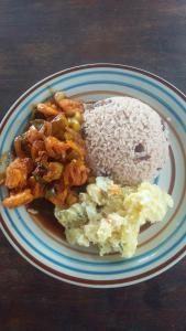 a plate of food with rice and a donut on it at Bastimentos Caribean Hotel in Bocas Town