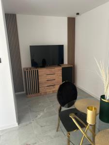 a living room with a tv and a chair and a table at Apartament Ostrowiec Świętokrzyski Browarna 4 in Ostrowiec Świętokrzyski +9 photos