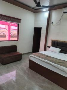 a bedroom with a bed and a window and a couch at Lords Hotel in Agra