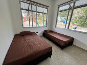a bedroom with two beds and two windows at Villa Majo in Nocaima
