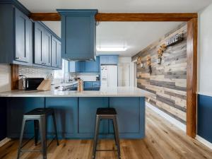a kitchen with blue cabinets and two bar stools at The Nest with Firepit & Backyard Oasis in Klamath Falls