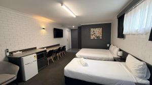 a hotel room with two beds and a desk and chairs at Blue Violet Motor Inn in Toowoomba +55 photos