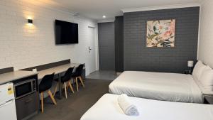 a hotel room with two beds and a bar with chairs at Blue Violet Motor Inn in Toowoomba