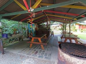 a patio with picnic tables and benches under a pavilion at Alouatta Lodge and Canopy in Cahuita