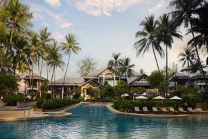 a resort swimming pool with chairs and palm trees at Dusit Thani Laguna Phuket in Bang Tao Beach
