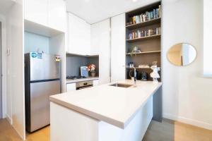 a kitchen with a white counter and a refrigerator at Boutique 1B2B HighRise Condo in CBD in Melbourne