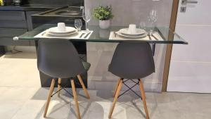 a glass table with two chairs and plates on it at Reserva Madero Loft in Natal