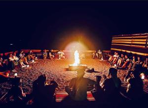 a crowd of people sitting around a fire pit at Starlit Wadi Rum camp in Wadi Rum